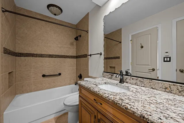 a bathroom with a granite countertop sink a toilet and bathtub