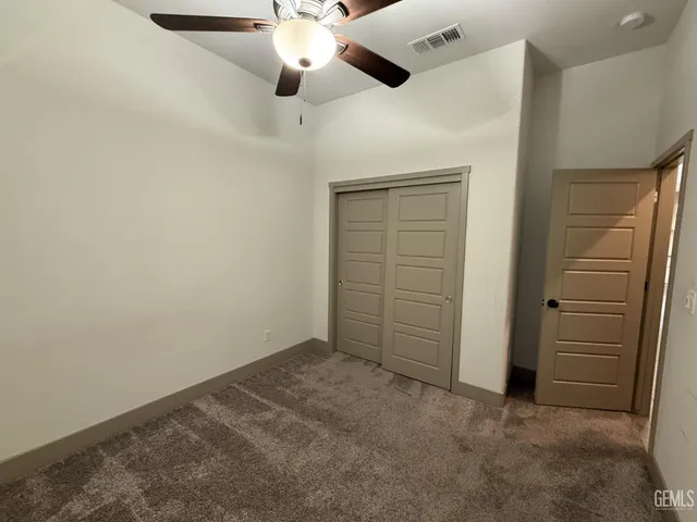 an empty room with closet and a chandelier fan