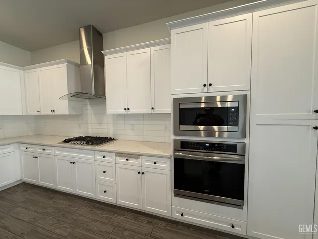 a kitchen with granite countertop white cabinets and appliances