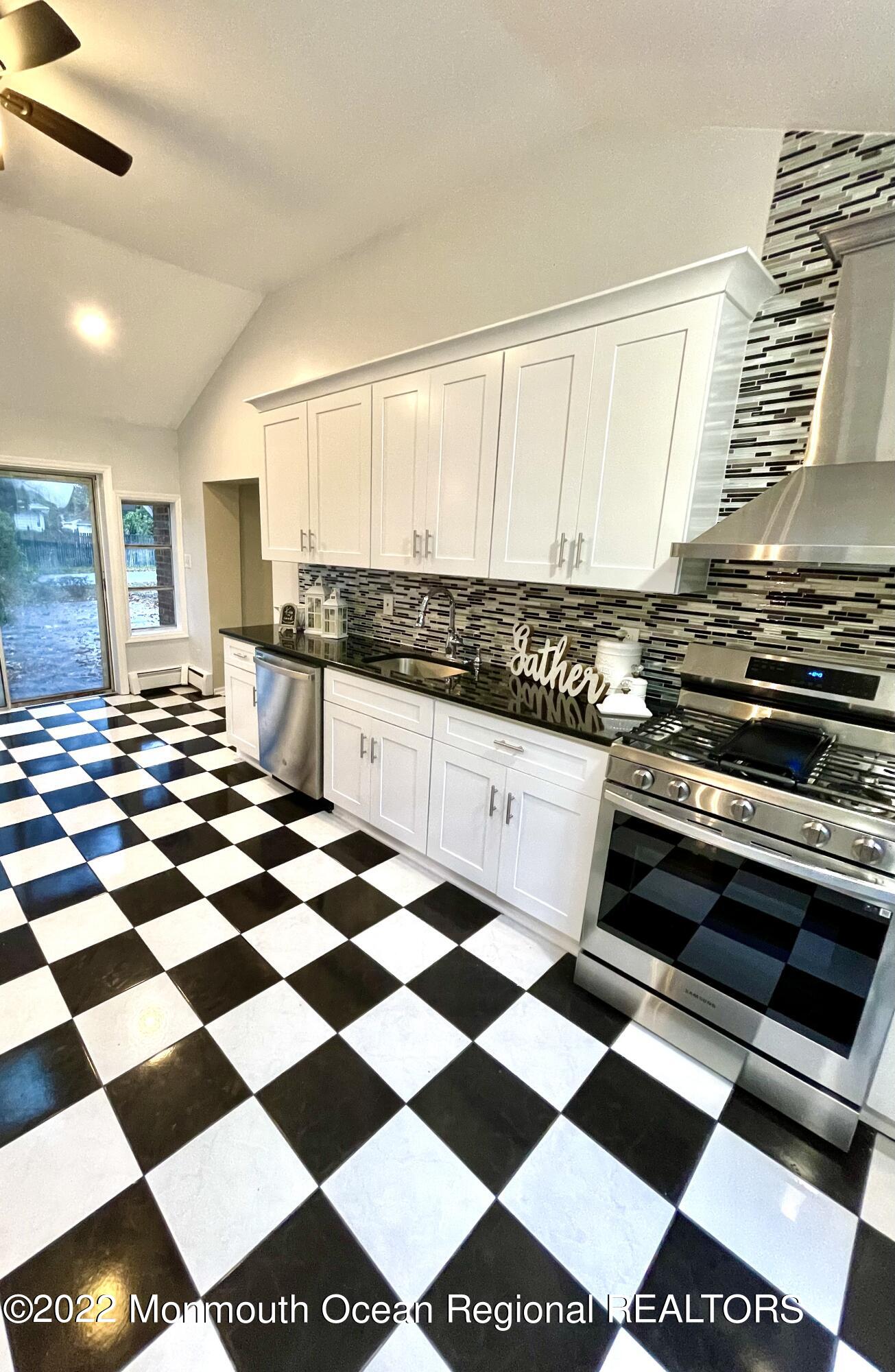 641 Thoroughfare Road Brick, NJ 08724 - Photo 14 of 48 a kitchen with a checkered floor and white cabinets