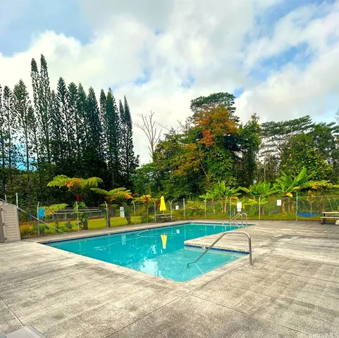a view of swimming pool with a yard and trees in the background