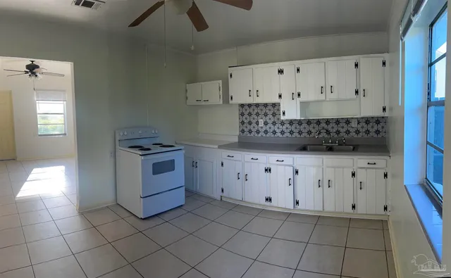 a kitchen with white cabinets and window