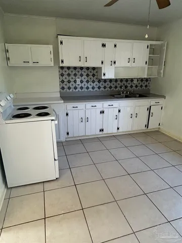 a kitchen with granite countertop a stove a sink and a refrigerator
