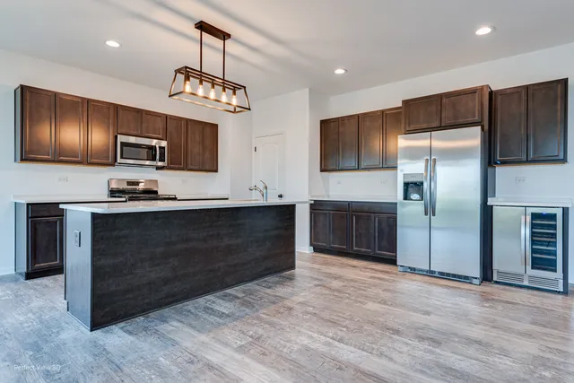 a kitchen with kitchen island granite countertop a refrigerator and a sink