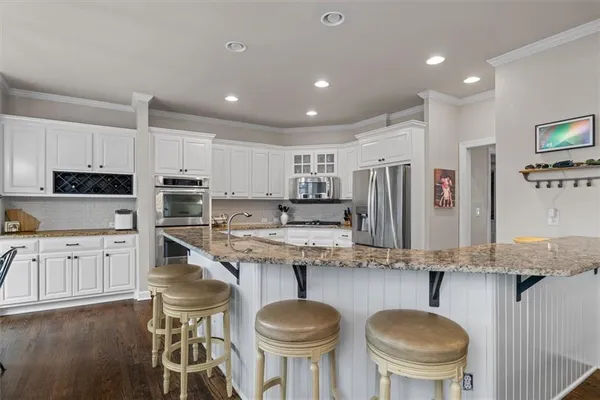 a kitchen with stainless steel appliances granite countertop a stove a sink a dining table and chairs