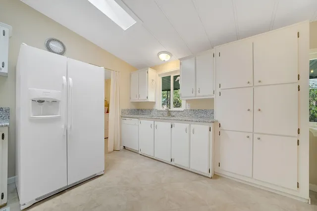 a kitchen with white cabinets and refrigerator