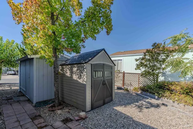 a view of a wooden house with a small yard and large tree