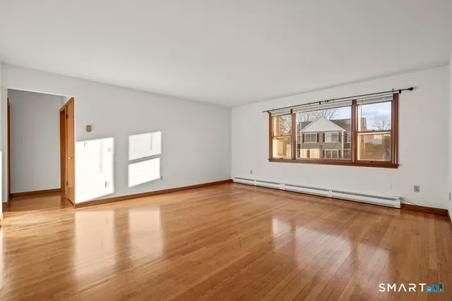 a view of an empty room with window and wooden floor