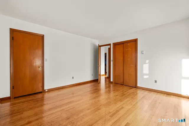 a view of an empty room with wooden floor and closet