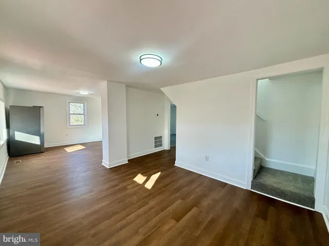 an empty room with wooden floor & windows