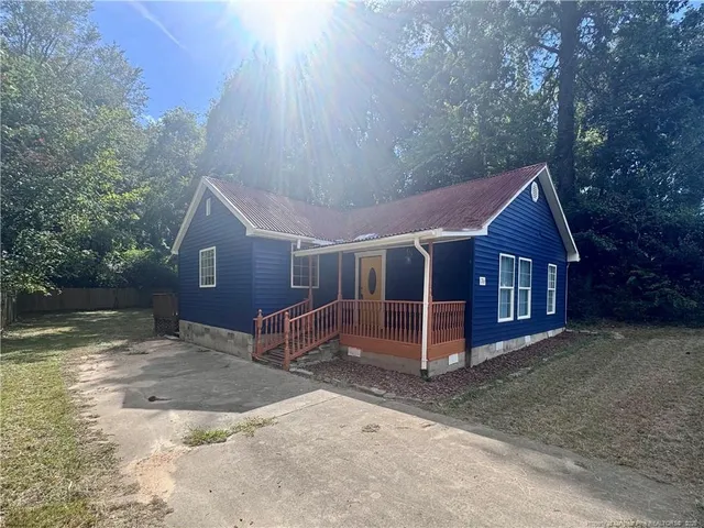 a view of a house with a yard and large tree