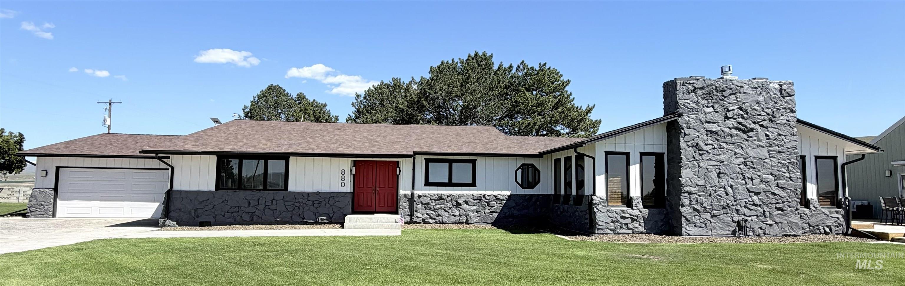 Contemporary ranch-style residence featuring a prominent stone chimney and a contrasting red entry door