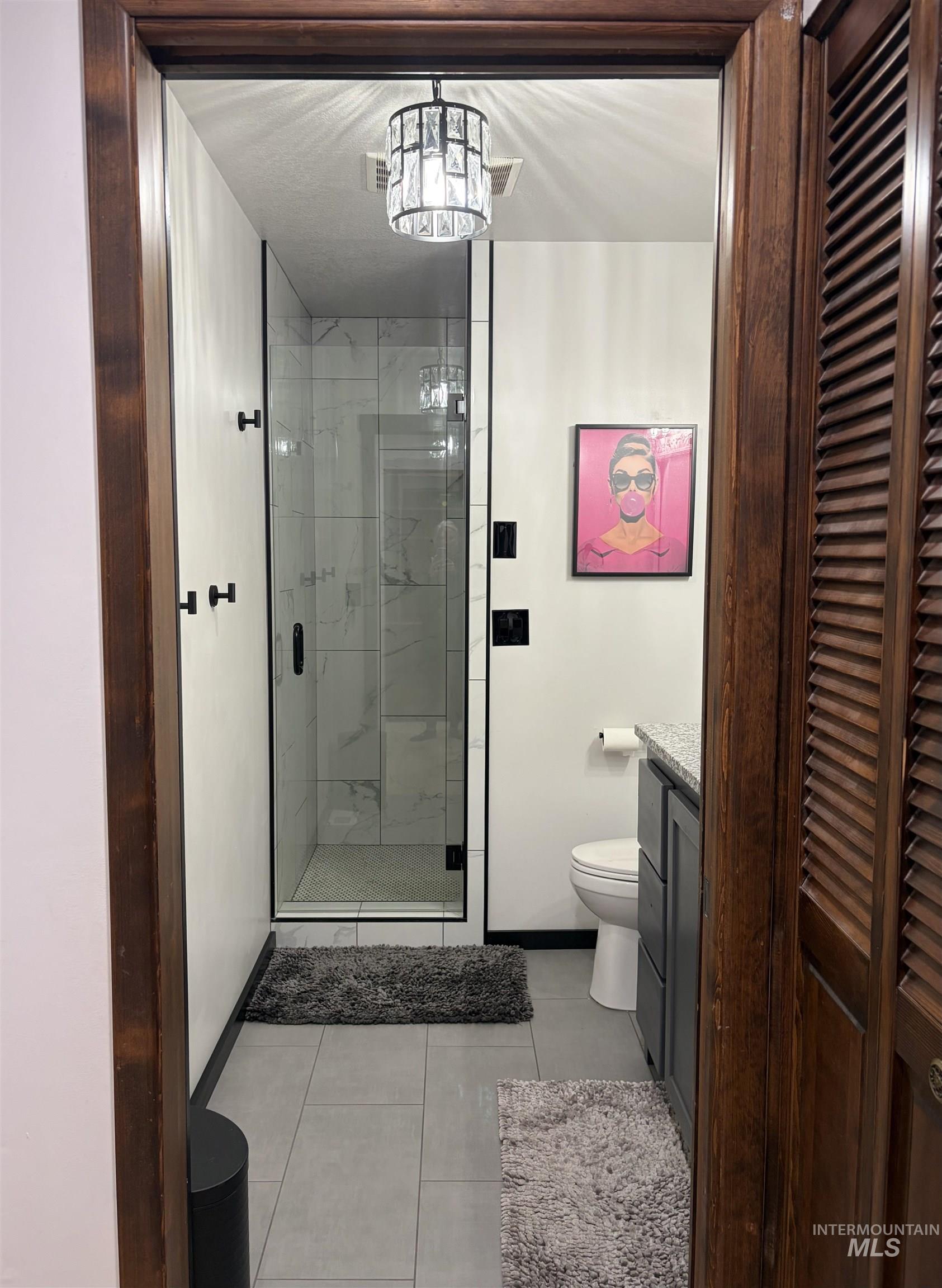 880 Jenkins Creek Road Weiser, ID 83672 - Photo 28 of 43 Framed entrance to a bathroom featuring a walk-in shower with clear glass enclosure and black trim, complemented by white subway tile walls