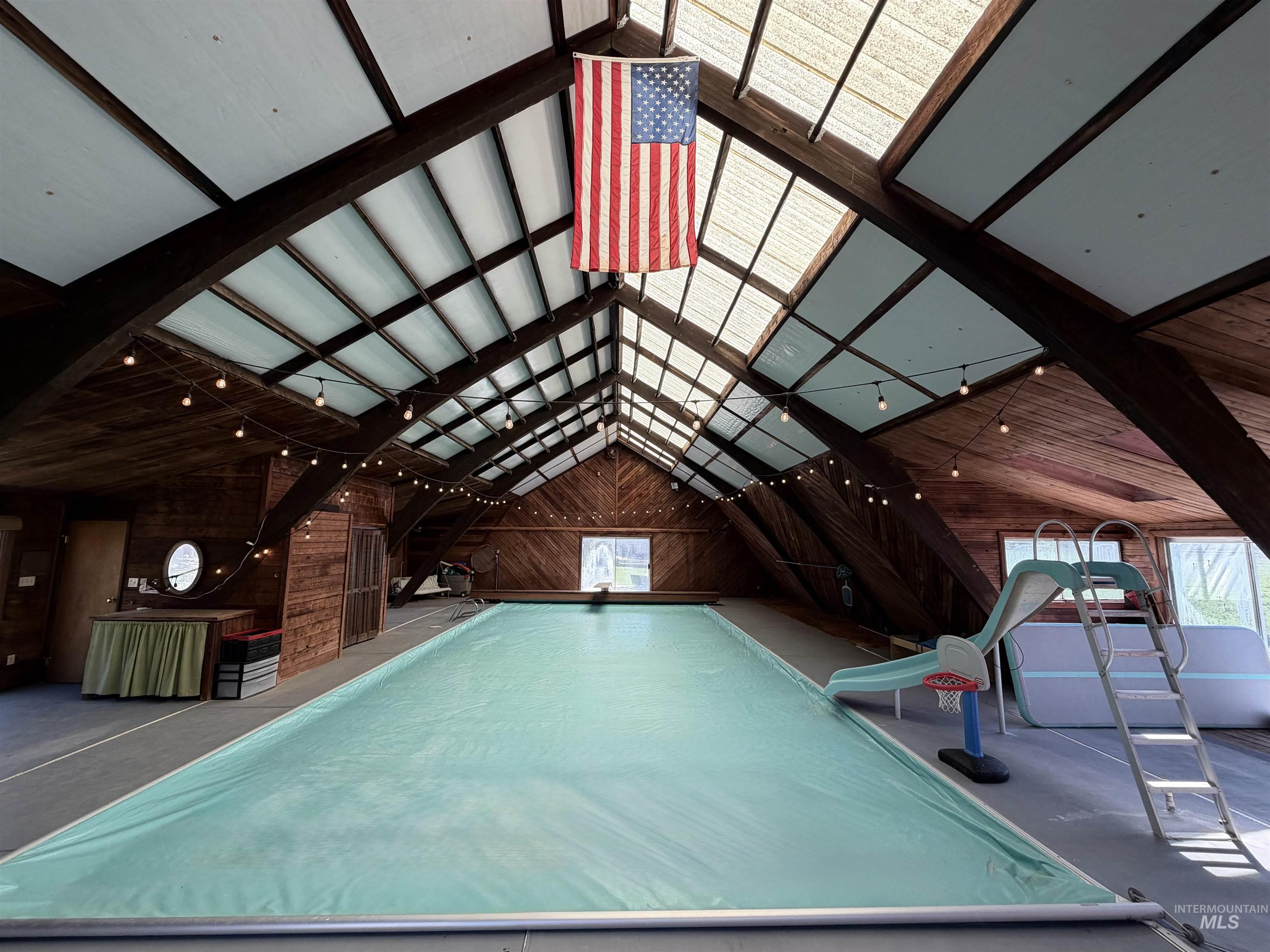 880 Jenkins Creek Road Weiser, ID 83672 - Photo 37 of 43 Indoor swimming pool area featuring a gabled roofline with skylight panels, exposed wood beams, and wood-paneled walls