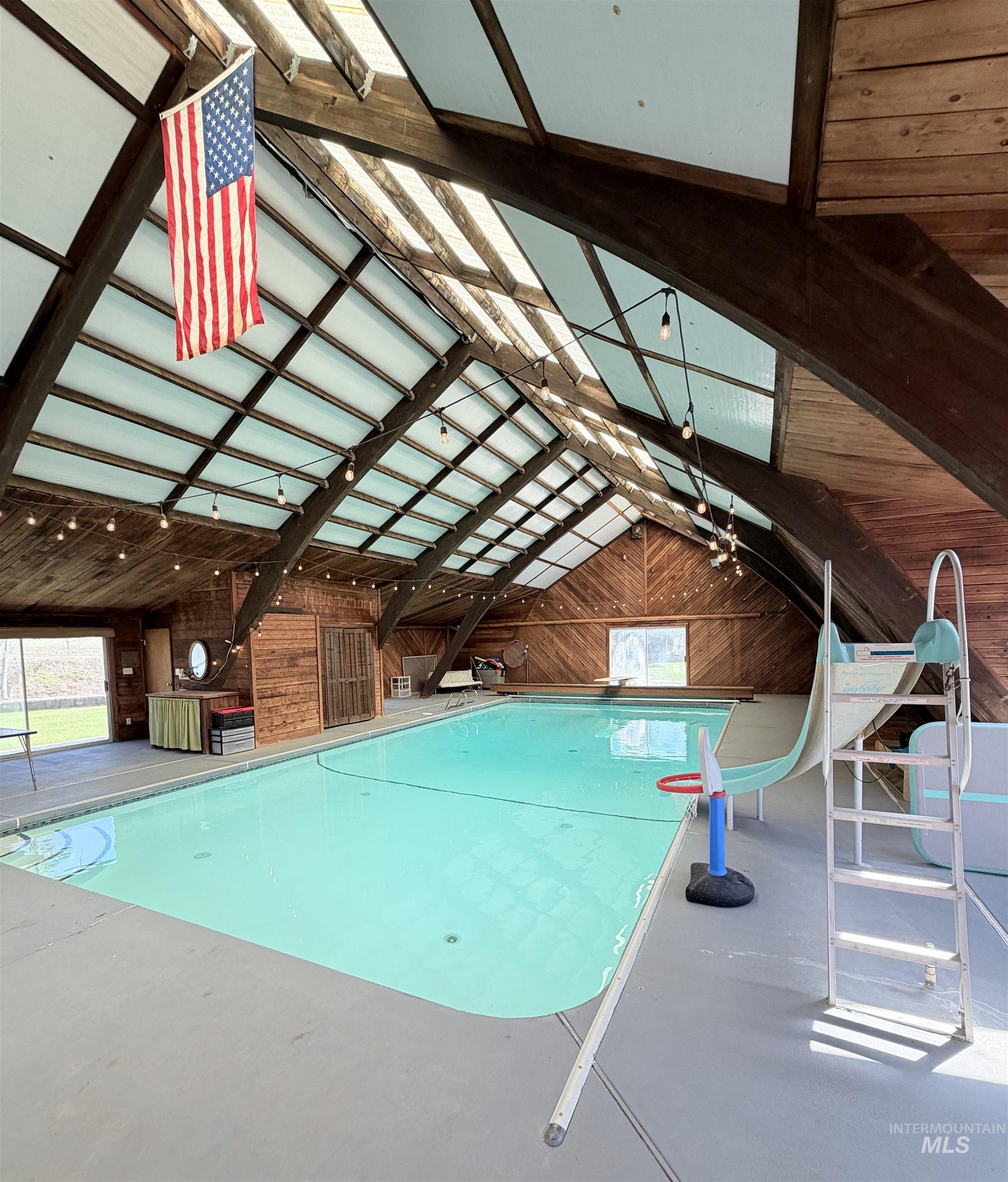 880 Jenkins Creek Road Weiser, ID 83672 - Photo 38 of 43 Indoor swimming pool featuring a vaulted wood-paneled ceiling with skylights, exposed wood beams, and string lighting