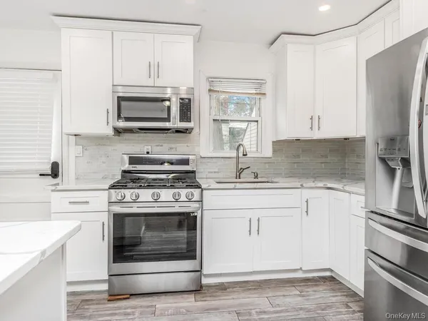 a kitchen with stainless steel appliances white cabinets a stove a sink and a microwave