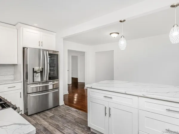 a kitchen with a refrigerator stainless steel appliances wooden floor and cabinets
