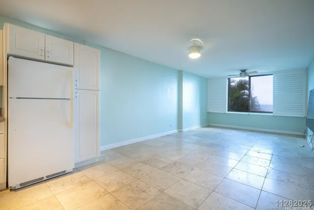 a view of an empty room with window and refrigerator