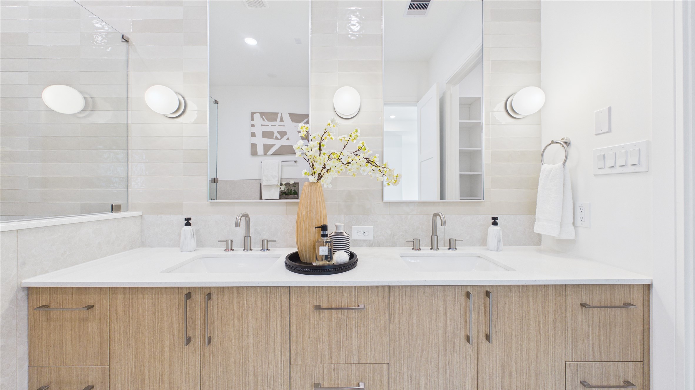 602 Skyland Terrace Way Houston, TX 77009 - Photo 31 of 40 This modern bathroom features a double vanity with sleek wood cabinets, large mirrors, and soft lighting. The neutral tones and elegant fixtures create a clean, inviting space perfect for a contemporary home.