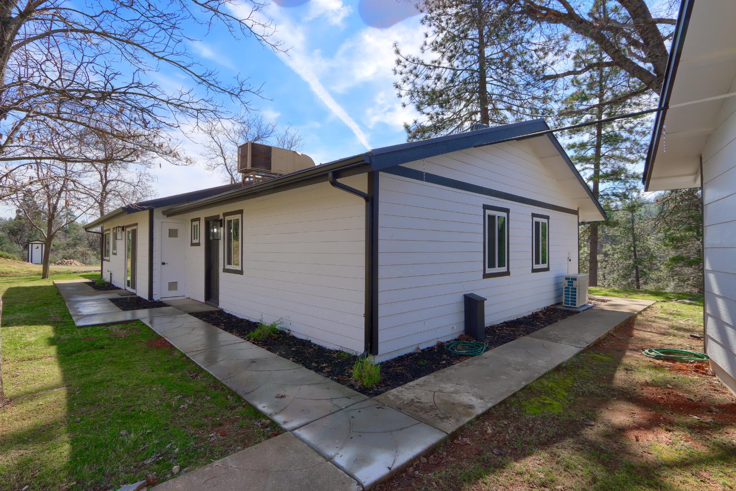 5518 East Whitlock Road Mariposa, CA 95338 - Photo 40 of 57 a view of a white house next to a yard with big trees
