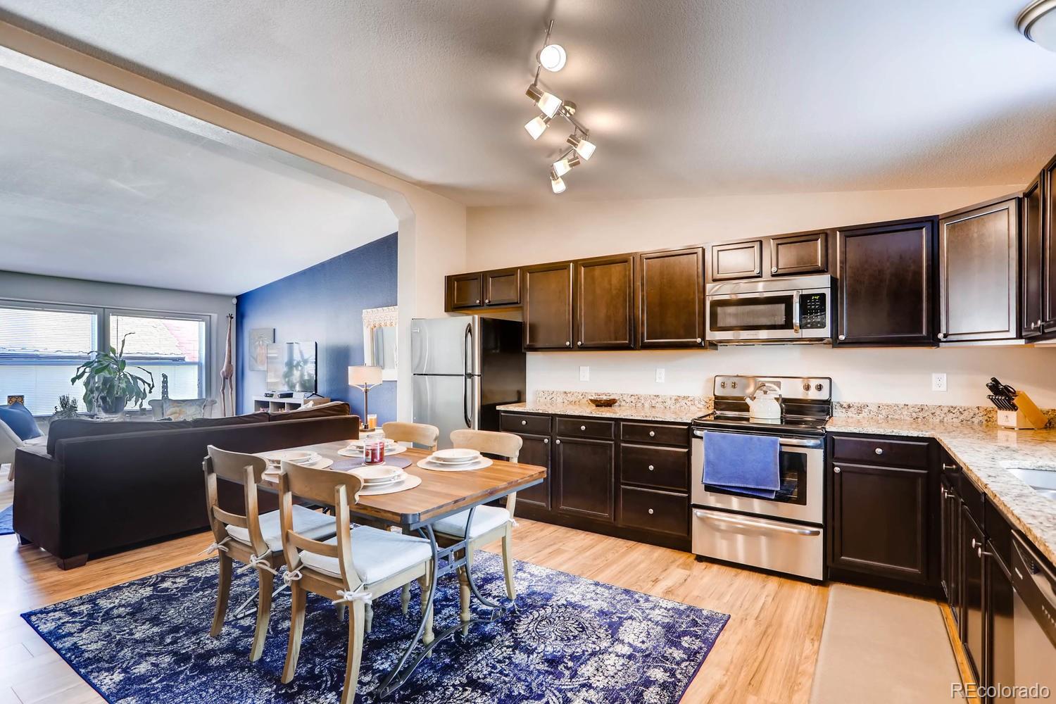 520 South Raleigh Street Denver, CO 80219 - Photo 14 of 27 a kitchen with stainless steel appliances granite countertop a sink dishwasher a stove a refrigerator with a dining table and chairs