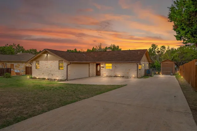 a view of a house with a big yard and large tree