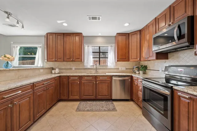 a kitchen with stainless steel appliances granite countertop wooden cabinets a stove top oven a sink and dishwasher