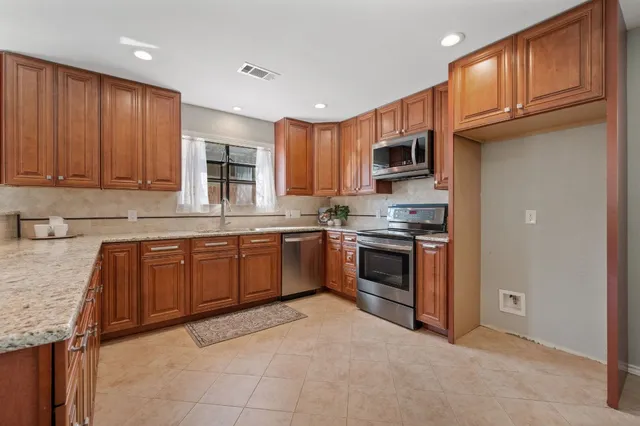 a kitchen with granite countertop a stove top oven sink and cabinets