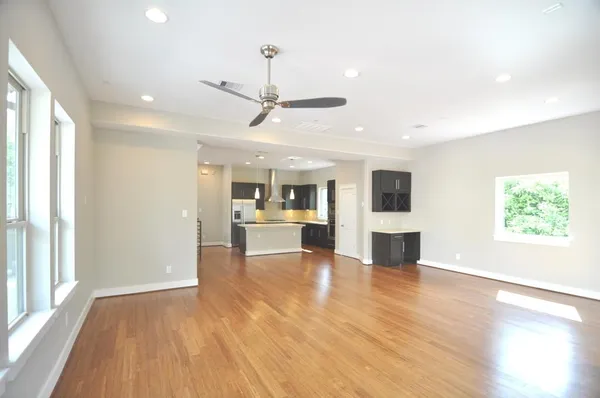 a view of a living room a kitchen with furniture wooden floor and a window