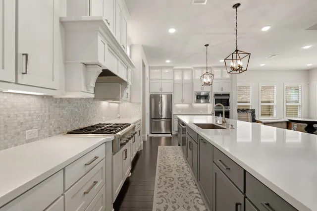 a kitchen with kitchen island stainless steel appliances a stove a sink a refrigerator cabinets and living room view