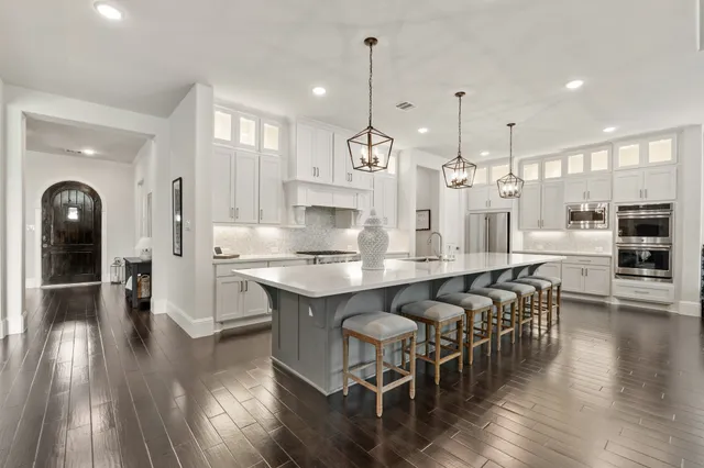 a kitchen with stainless steel appliances a stove a sink a oven a refrigerator and chairs