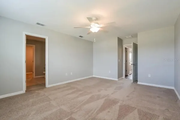 an empty room with closet and a ceiling fan