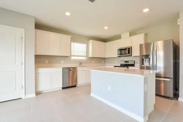 a kitchen with a refrigerator a stove top oven a sink and cabinets