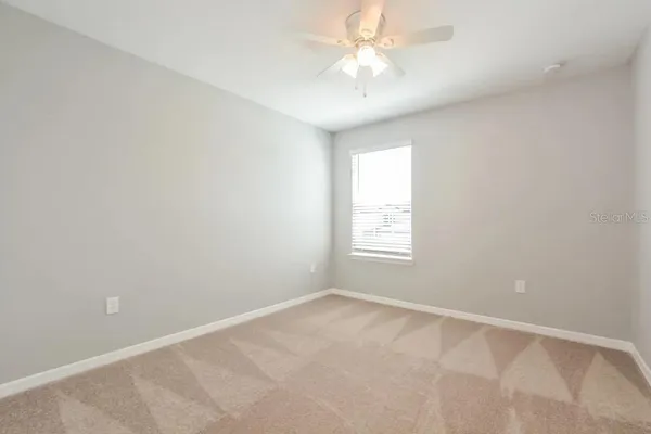 an empty room with a window and a fan