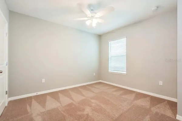an empty room with a window and a ceiling fan