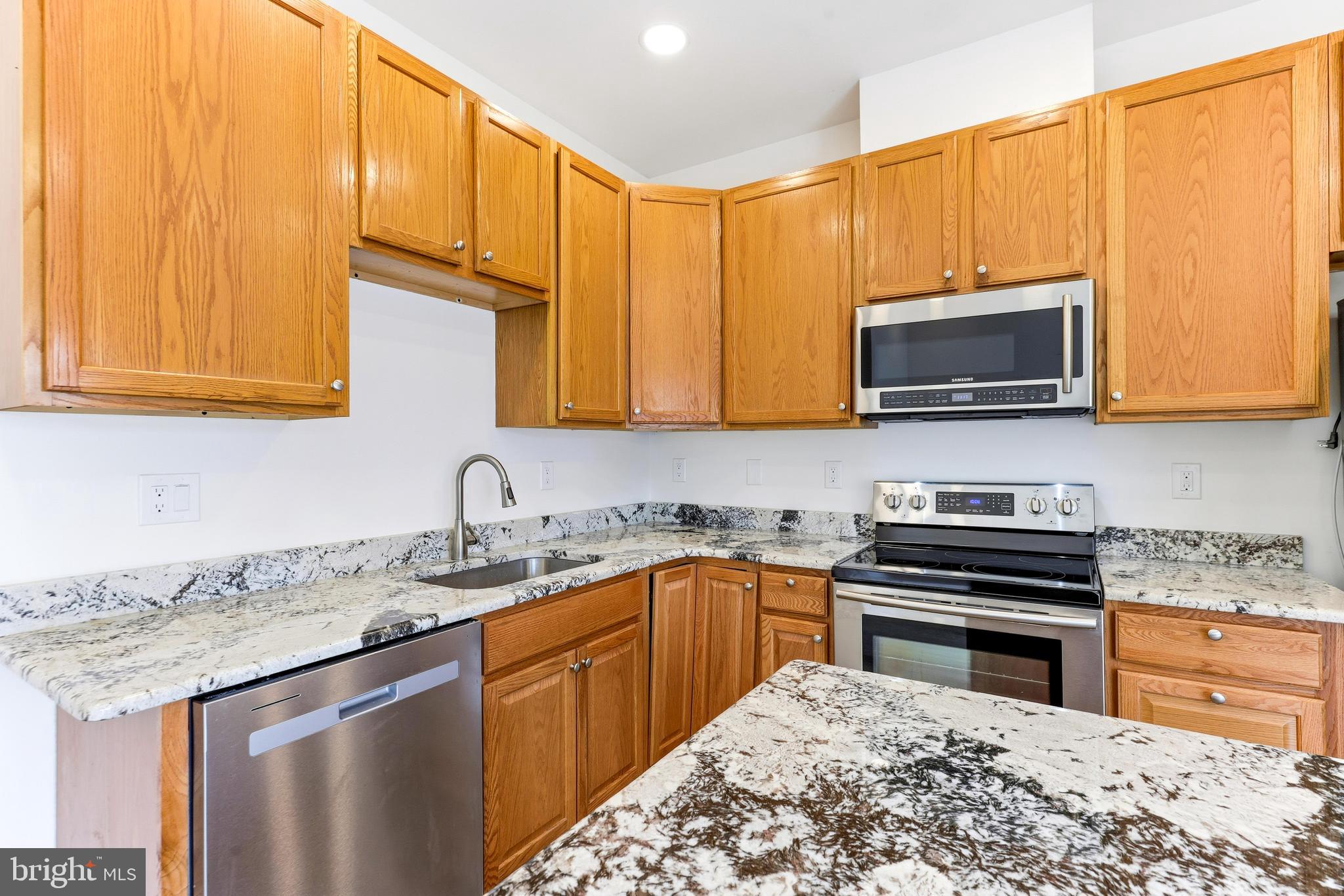 8428 Gold Sunset Way Columbia, MD 21045 - Photo 12 of 43 a kitchen with stainless steel appliances kitchen island granite countertop a sink stove and microwave