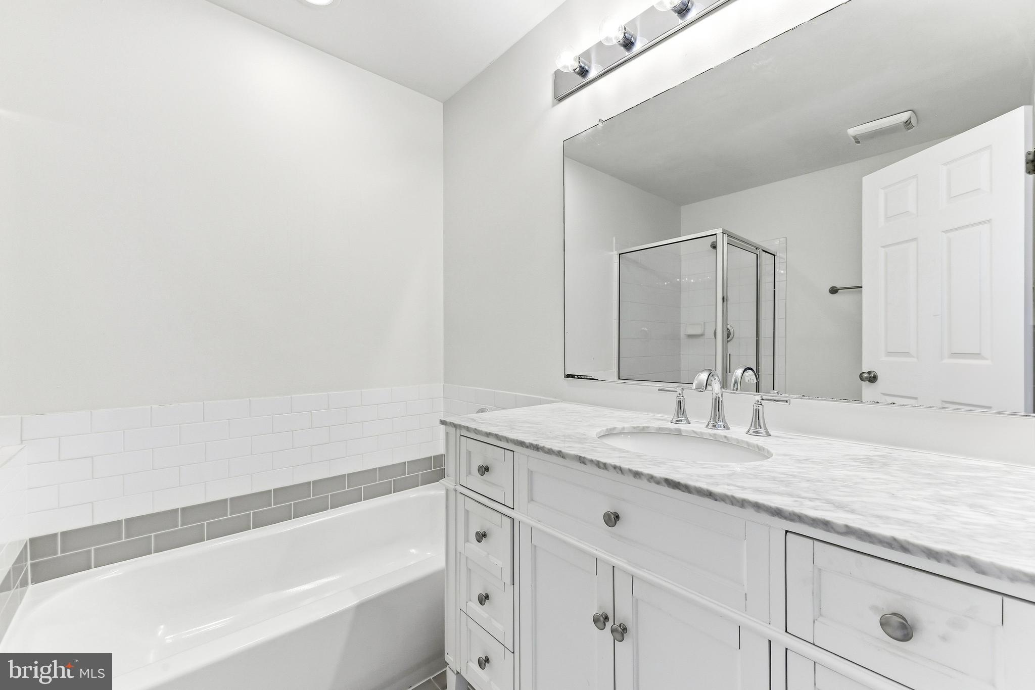 8428 Gold Sunset Way Columbia, MD 21045 - Photo 28 of 43 a bathroom with a granite countertop sink and a bathtub