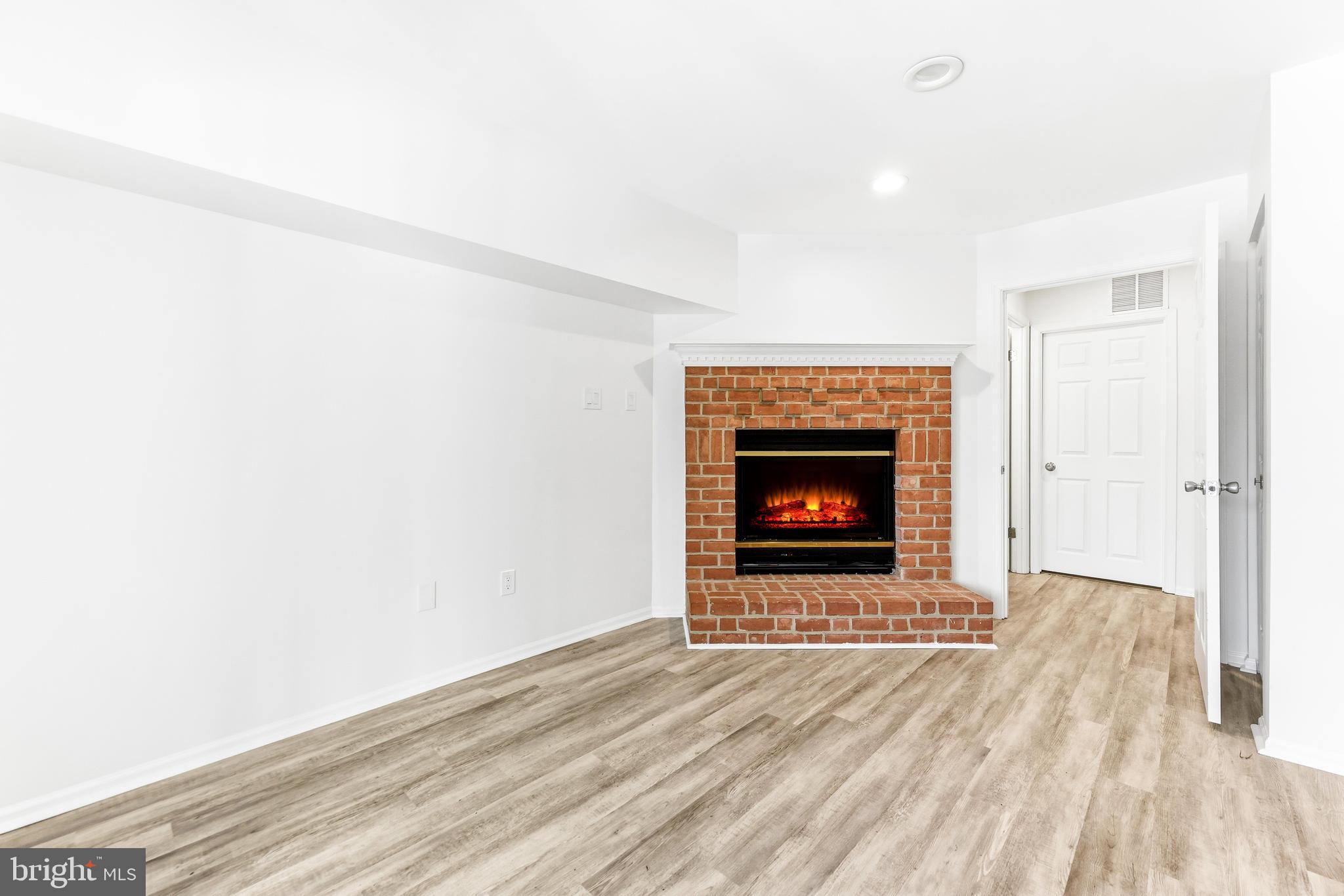 8428 Gold Sunset Way Columbia, MD 21045 - Photo 33 of 43 a room with a fireplace and a wooden floor