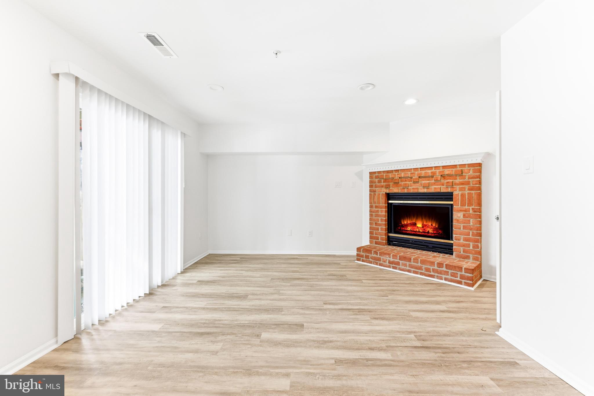 8428 Gold Sunset Way Columbia, MD 21045 - Photo 35 of 43 a view of an empty room with wooden floor fireplace and a window