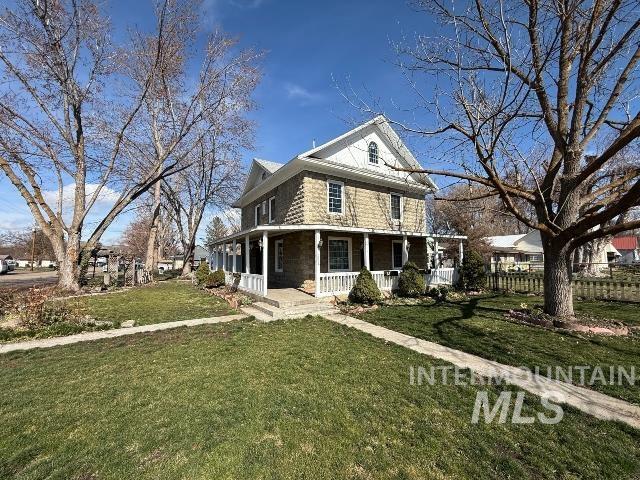 Farmhouse-style home with a porch and a front lawn