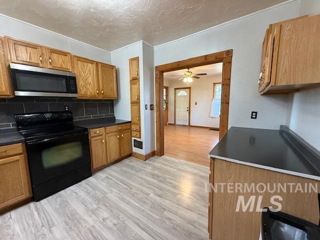 902 East Main Street Weiser, ID 83672 - Photo 11 of 45 Kitchen featuring black electric range, dark countertops, wood finish cabinetry, stainless steel microwave, and light wood-type flooring