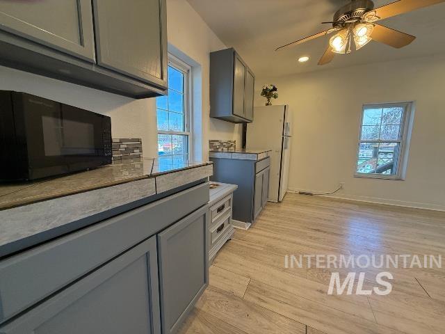 902 East Main Street Weiser, ID 83672 - Photo 13 of 45 Kitchen with gray cabinets, a ceiling fan, black microwave, light wood finished floors, and freestanding refrigerator