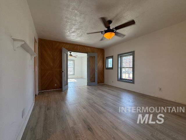 902 East Main Street Weiser, ID 83672 - Photo 16 of 45 Unfurnished room with a ceiling fan, wood finished floors, wood walls, and a textured ceiling