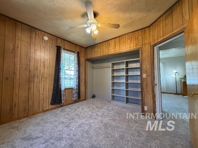 902 East Main Street Weiser, ID 83672 - Photo 19 of 45 Unfurnished bedroom with a ceiling fan, wooden walls, carpet flooring, a textured ceiling, and a closet