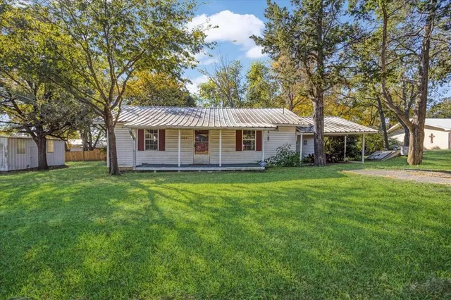 a front view of a house with a garden and tree
