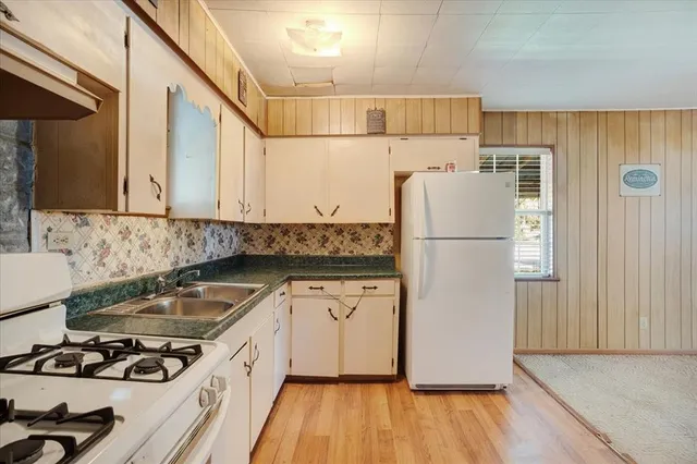 a kitchen with a refrigerator a stove and wooden floor
