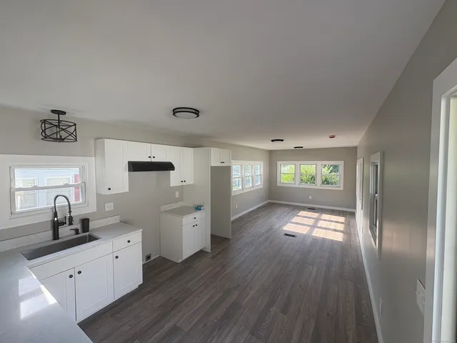 a view of a hallway with wooden floor and two windows