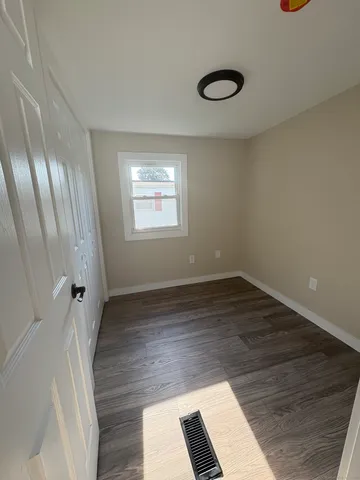 a view of an empty room with wooden floor and windows