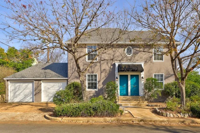 a front view of a house with a yard and potted plants