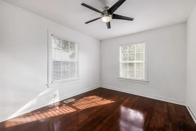 a view of an empty room with a window and wooden floor